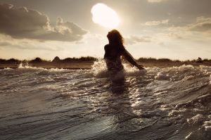 Young woman on sea embracing the the world and the waves
